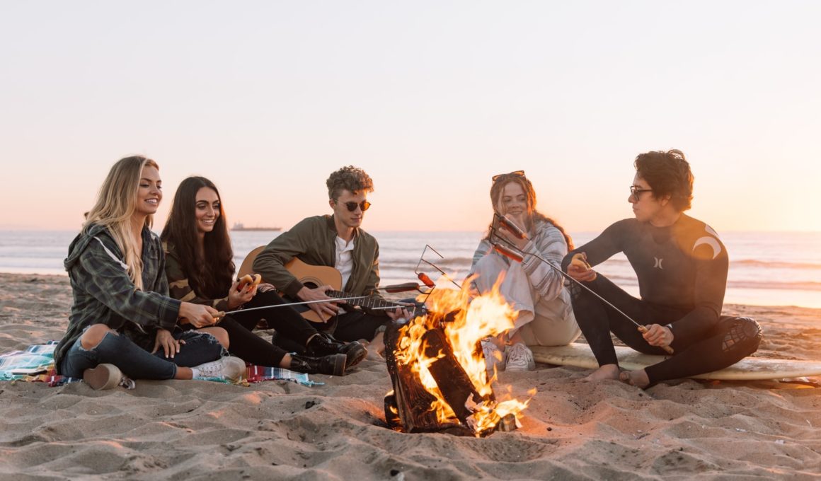 group of people sitting on ground with bonfire during daytime