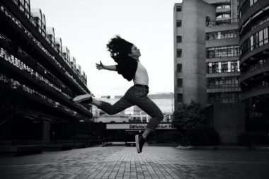 woman jumps on grayscale photography